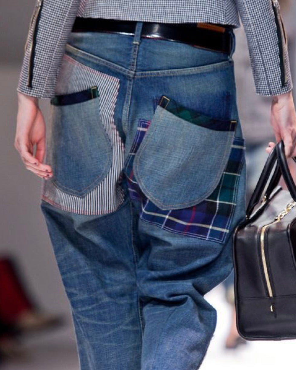Person wearing patchwork jeans with a plaid pattern, holding a black handbag.